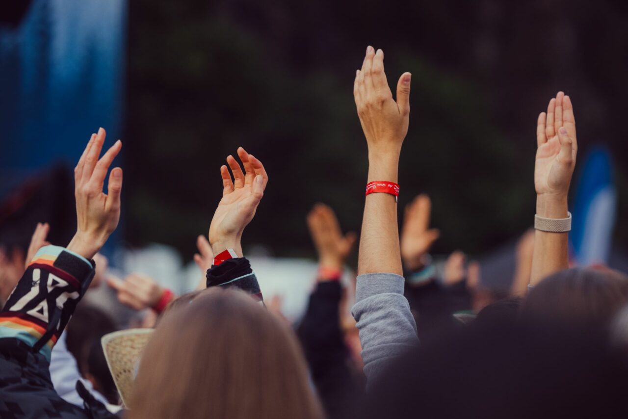 in die luft gestreckte hände mit rotem band an den handgelenken